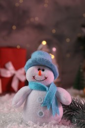 Photo of Funny snowman figure and fir branch on artificial snow, closeup