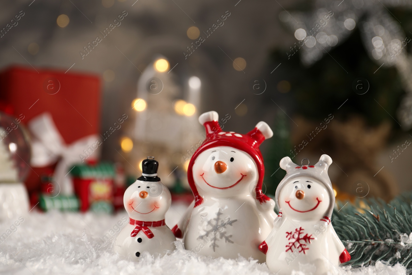 Photo of Funny snowmen figures and fir branch on artificial snow, closeup