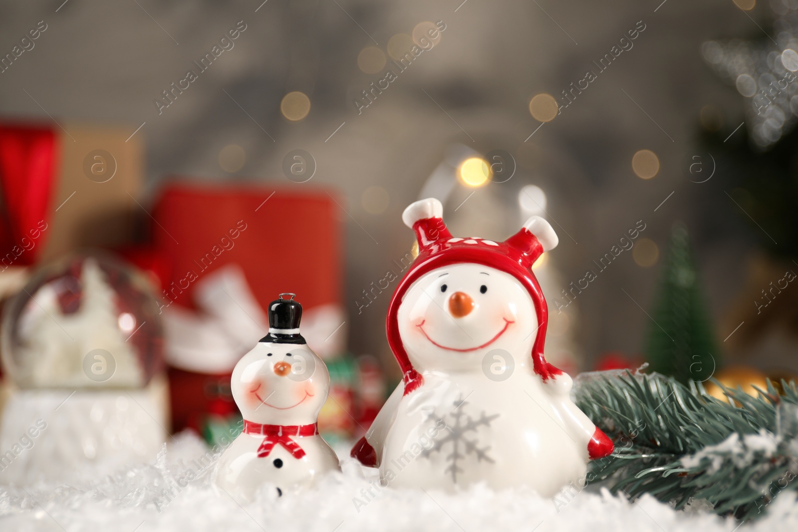 Photo of Funny snowmen figures and fir branch on artificial snow, closeup