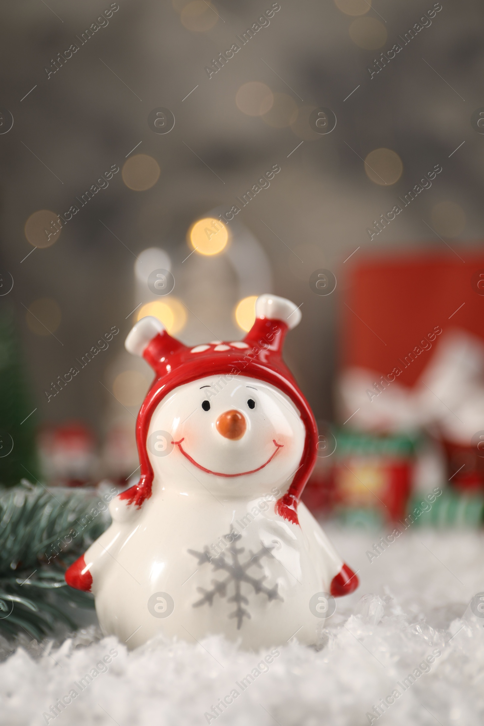 Photo of Funny snowman figure and fir branch on artificial snow, closeup