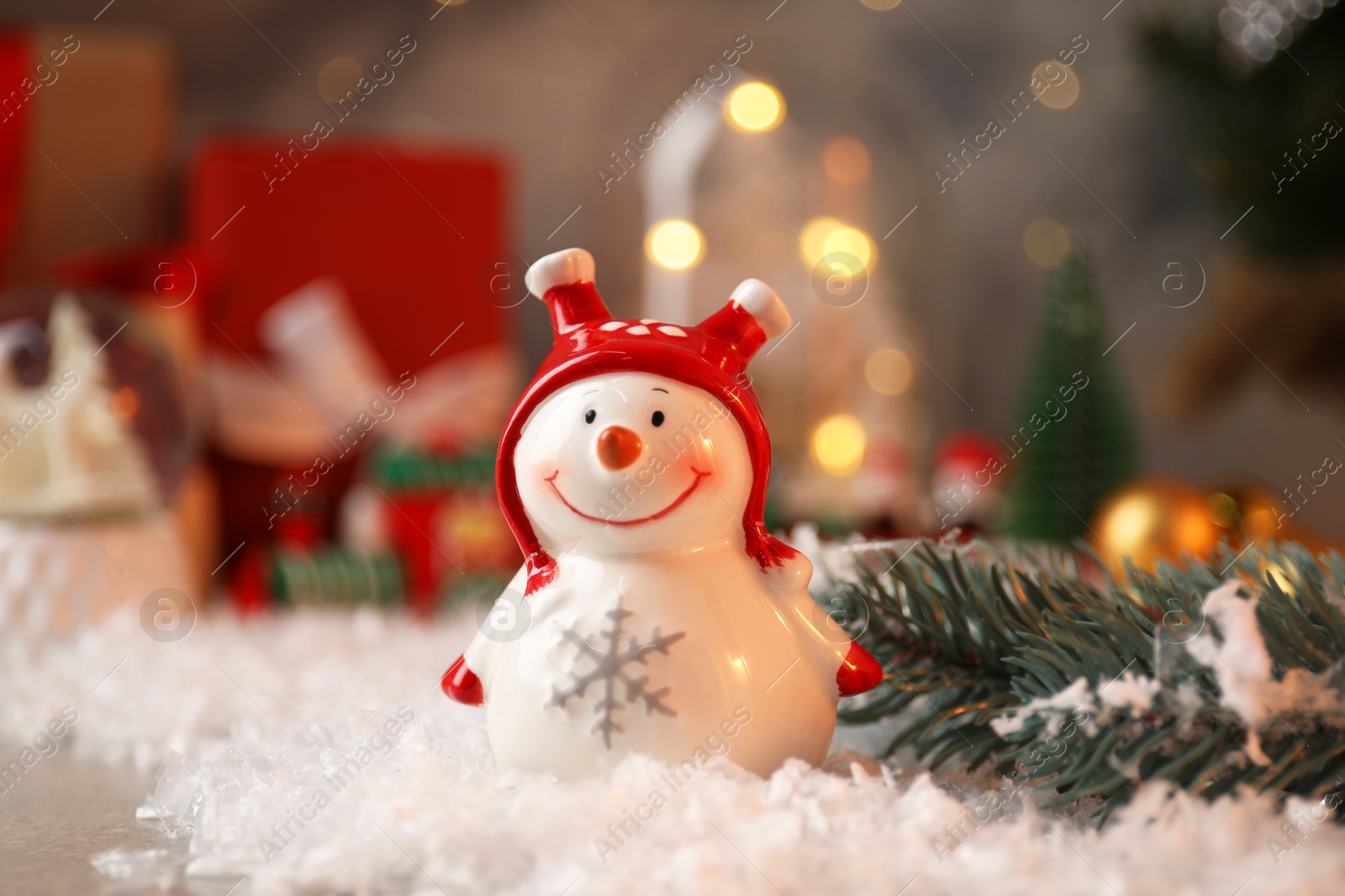 Photo of Funny snowman figure and Christmas decor on table, closeup