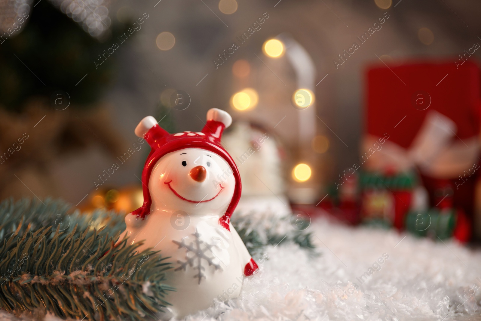 Photo of Funny snowman figure and fir branch on artificial snow, closeup. Space for text