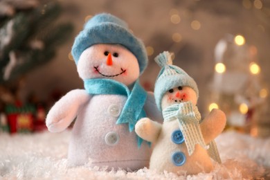 Photo of Funny snowmen figures on artificial snow, closeup