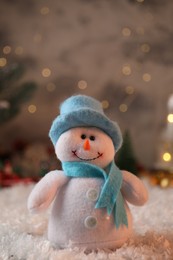 Photo of Funny snowman figure in hat on artificial snow, closeup