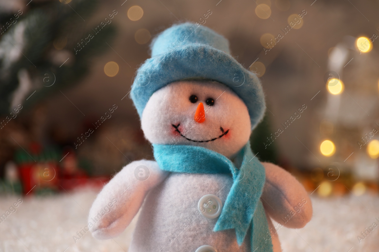 Photo of Funny snowman figure in hat on artificial snow, closeup