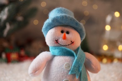 Photo of Funny snowman figure in hat on artificial snow, closeup