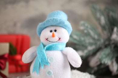 Photo of Funny snowman figure in hat on table, closeup