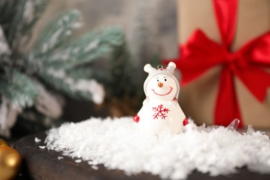 Photo of Funny snowman figure and artificial snow on table