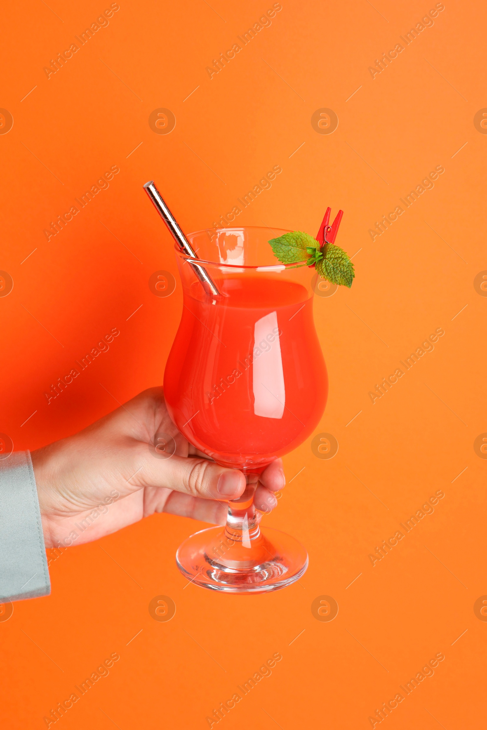 Photo of Woman with glass of refreshing cocktail on orange background, closeup