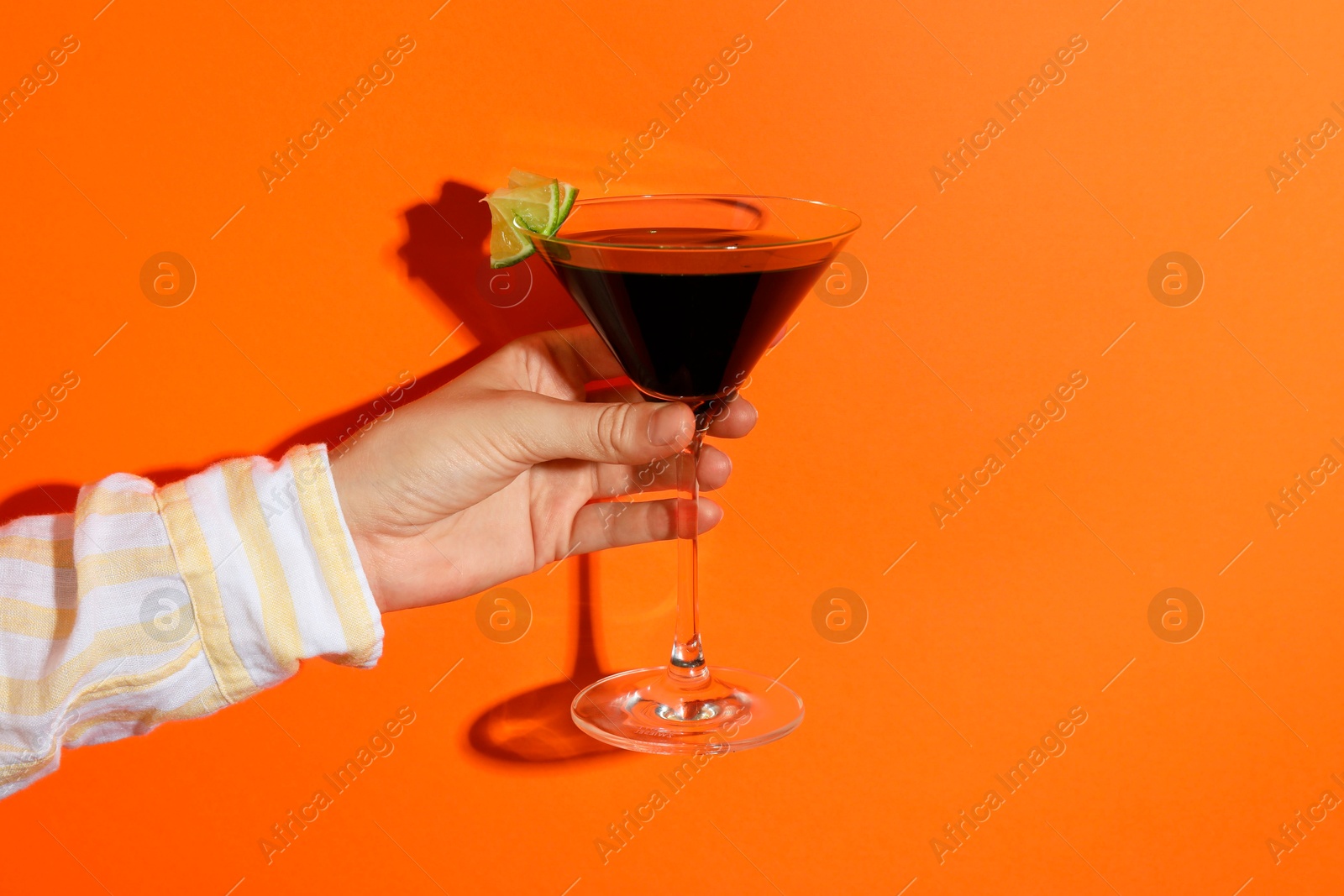 Photo of Woman with glass of refreshing cocktail on orange background, closeup