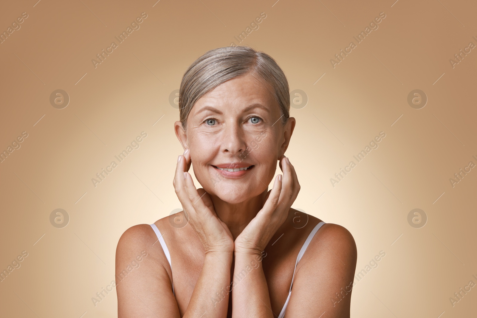 Photo of Face massage. Beautiful woman with healthy skin on beige background