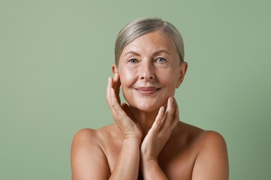 Face massage. Beautiful woman with healthy skin on light green background