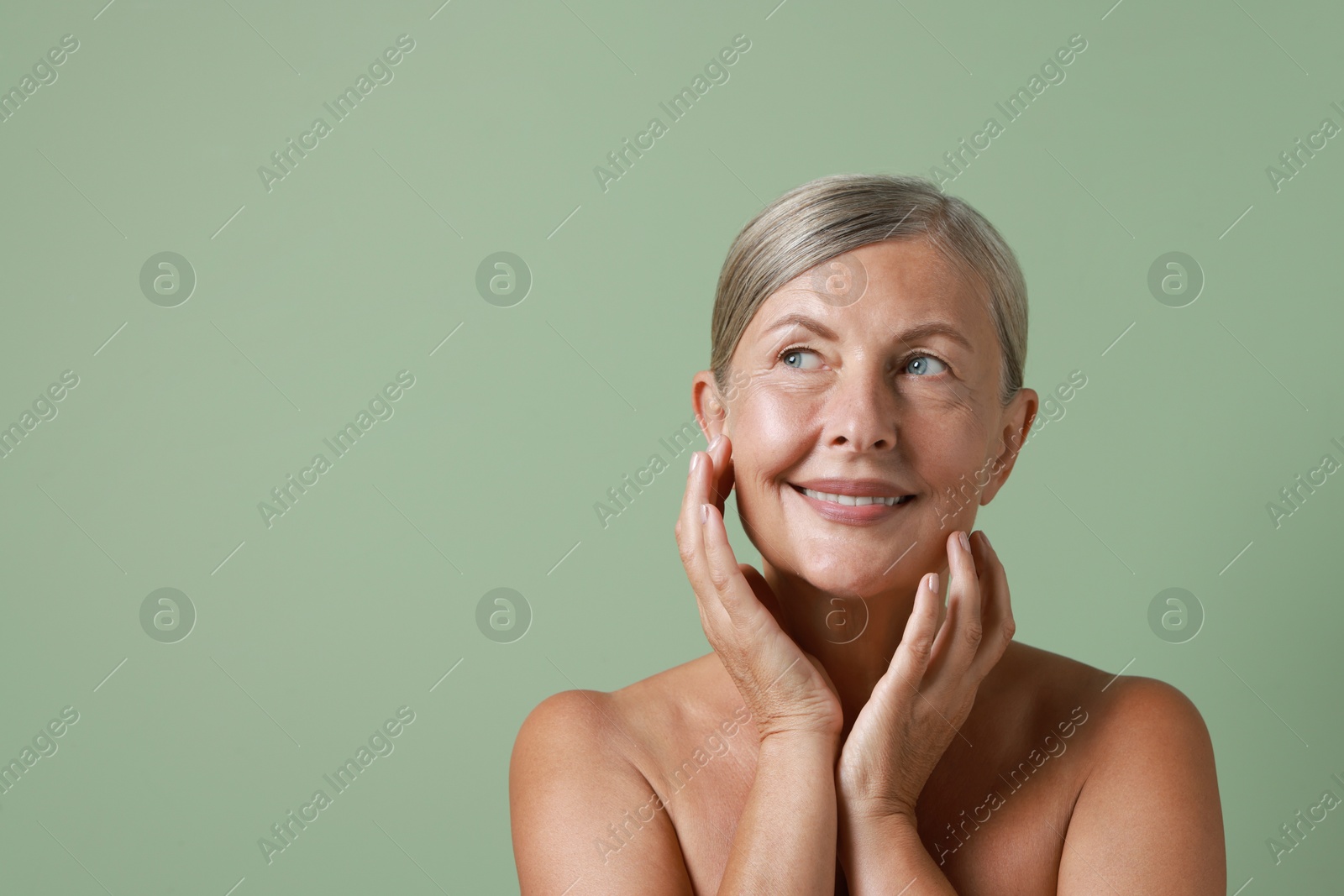 Photo of Face massage. Beautiful woman with healthy skin on light green background, space for text