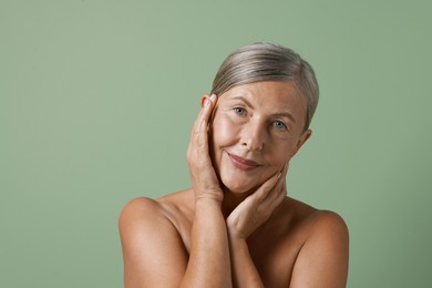 Face massage. Beautiful woman with healthy skin on light green background