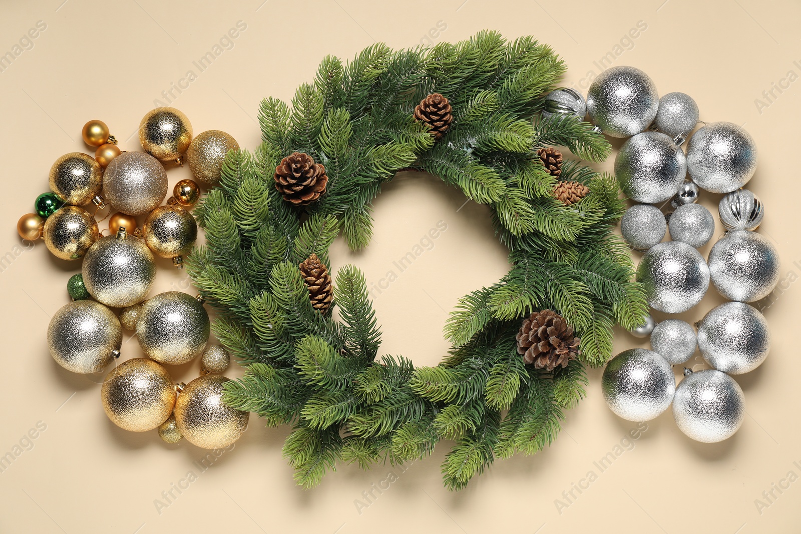 Photo of Christmas wreath with cones and baubles on beige background, flat lay