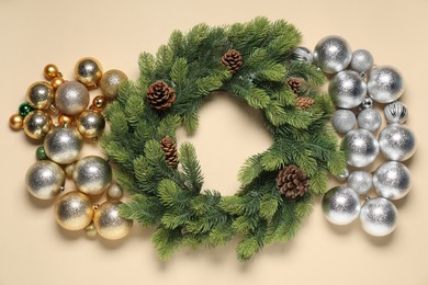 Photo of Christmas wreath with cones and baubles on beige background, flat lay