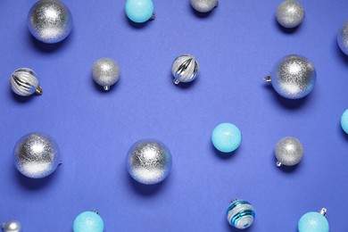 Photo of Different shiny baubles on blue background, flat lay