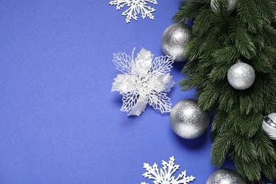 Photo of Fir tree branches, shiny baubles and decorative snowflakes on blue background, flat lay. Space for text