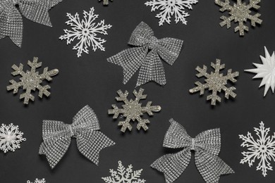 Photo of Flat lay composition with decorative snowflakes and bows on black background