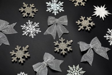 Photo of Composition with decorative snowflakes and bows on black background, above view