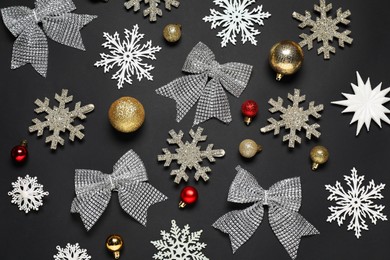 Flat lay composition with decorative snowflakes, baubles and bows on black background