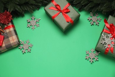 Photo of Different Christmas decor and gift boxes on green background, flat lay. Space for text