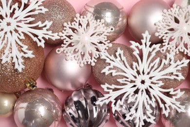 Photo of Shiny baubles and decorative snowflakes on pink background, flat lay