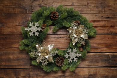 Christmas wreath with cones and decorative snowflakes on wooden table, top view