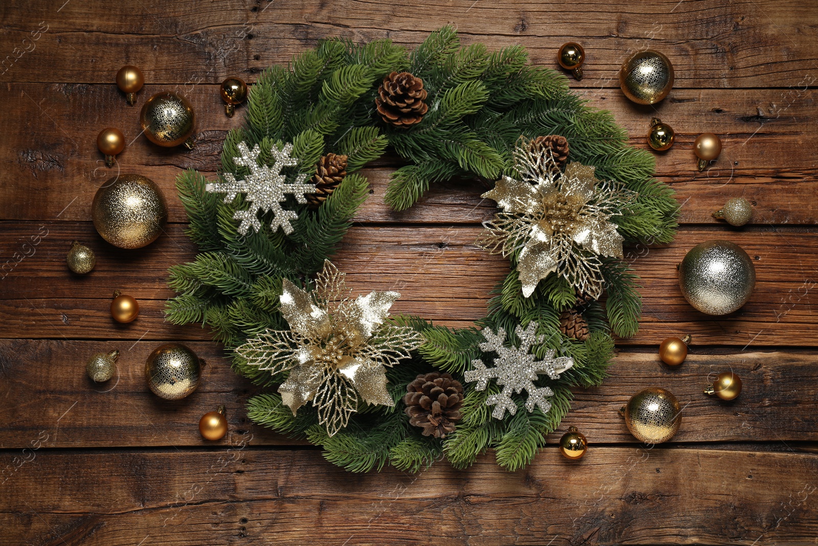 Photo of Christmas wreath with cones, baubles and decorative snowflakes on wooden table, flat lay