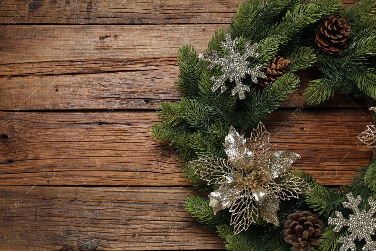 Photo of Christmas wreath with cones and decorative snowflakes on wooden table, top view. Space for text