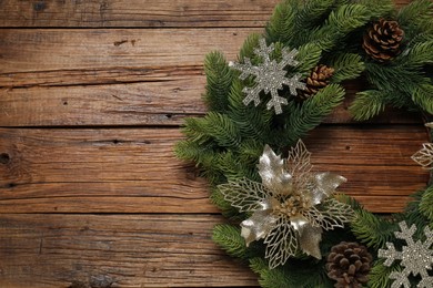 Christmas wreath with cones and decorative snowflakes on wooden table, top view. Space for text