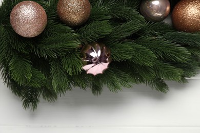 Photo of Fir tree branches and baubles on white wooden table, top view. Space for text