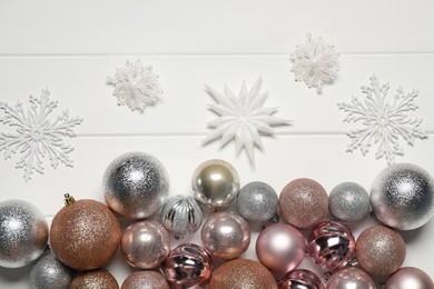 Photo of Different baubles and decorative snowflakes on white wooden table, flat lay