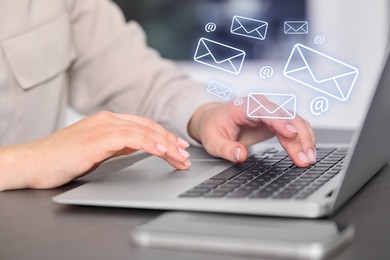 Image of Woman using laptop at table, closeup. E-mail address signs and envelopes over computer