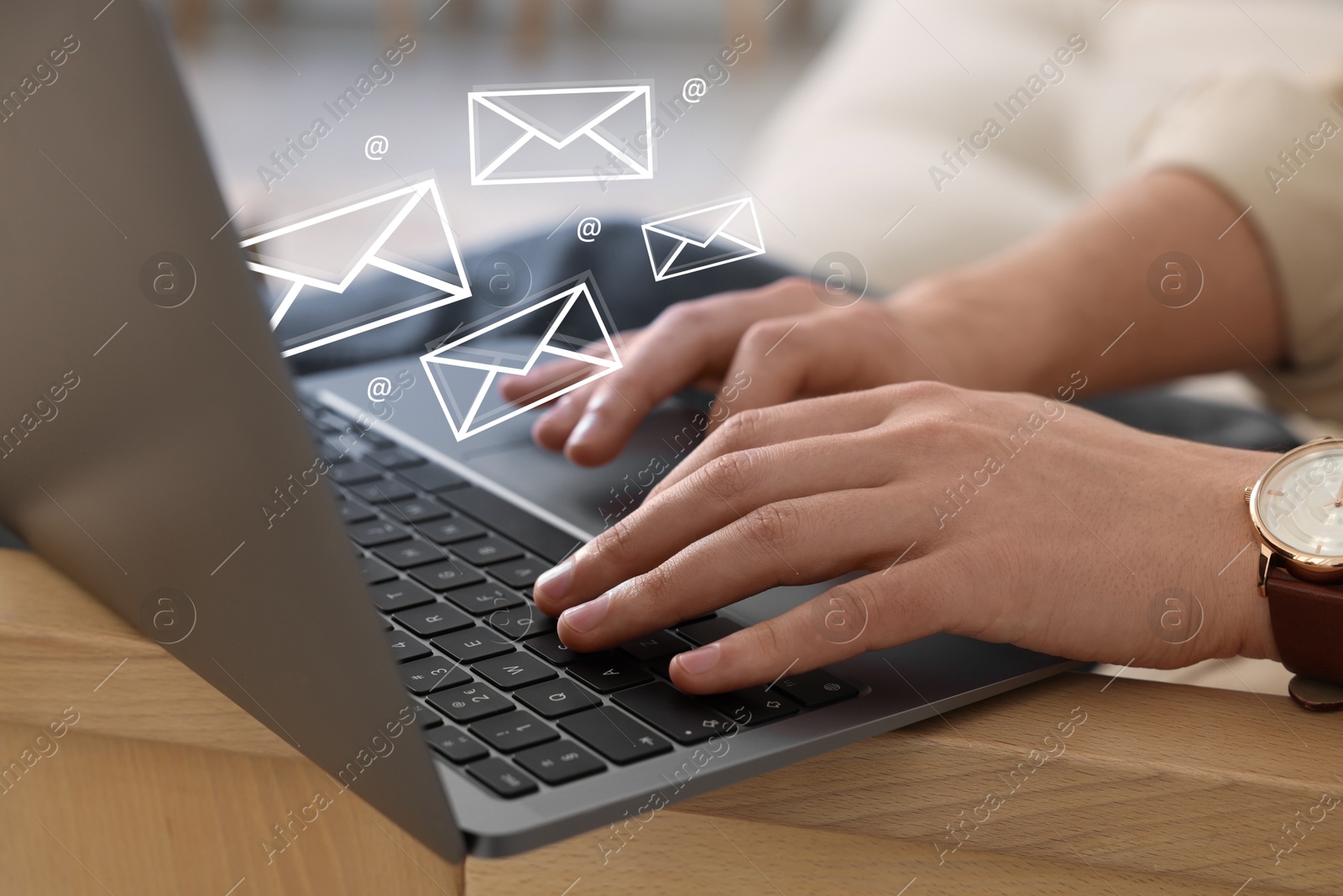 Image of Man using laptop at table, closeup. E-mail address signs and envelopes over computer