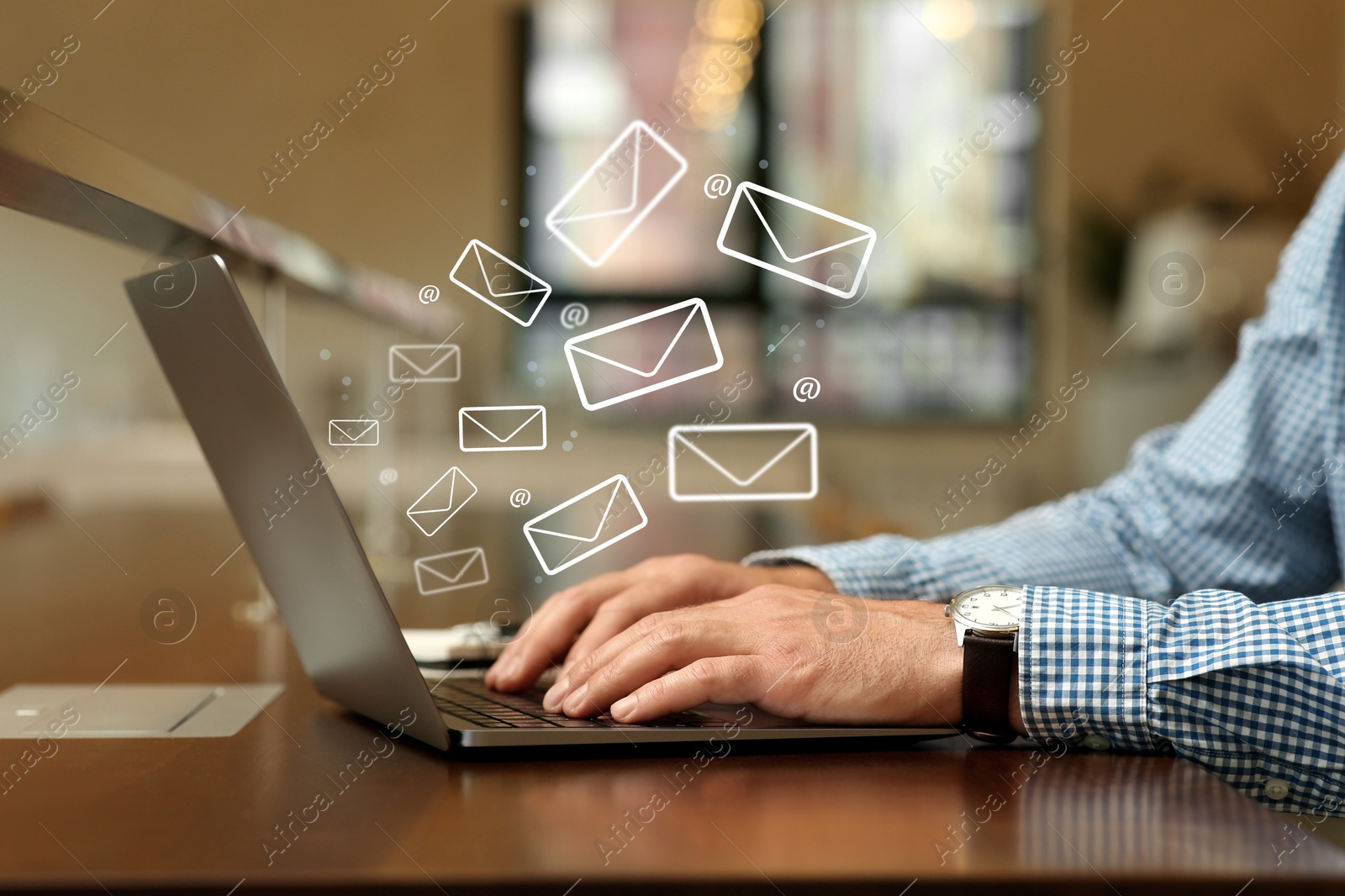 Image of Man using laptop at table, closeup. E-mail address signs and envelopes over computer