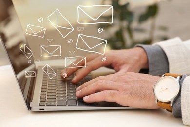 Image of Man using laptop at table, closeup. E-mail address signs and envelopes over computer