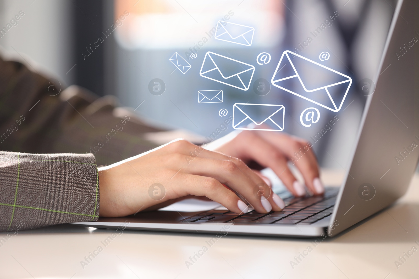 Image of Woman using laptop at table, closeup. E-mail address signs and envelopes over computer