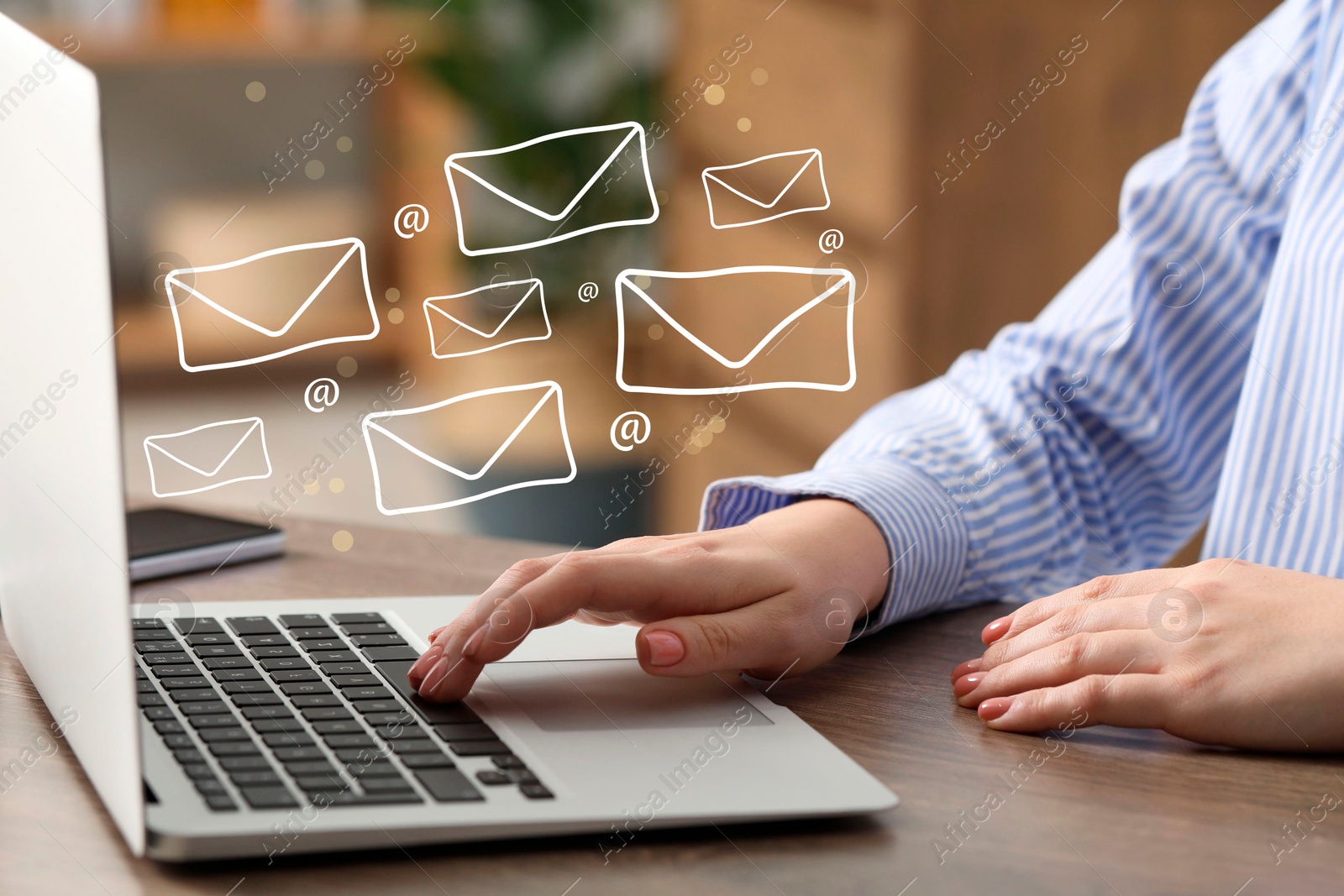 Image of Woman using laptop at table, closeup. E-mail address signs and envelopes over computer