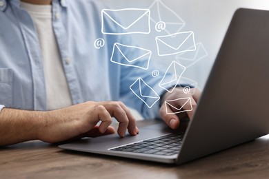 Image of Man using laptop at table, closeup. E-mail address signs and envelopes over computer