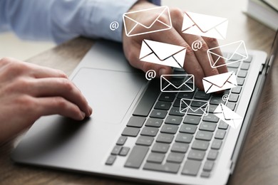 Image of Man using laptop at table, closeup. E-mail address signs and envelopes over computer