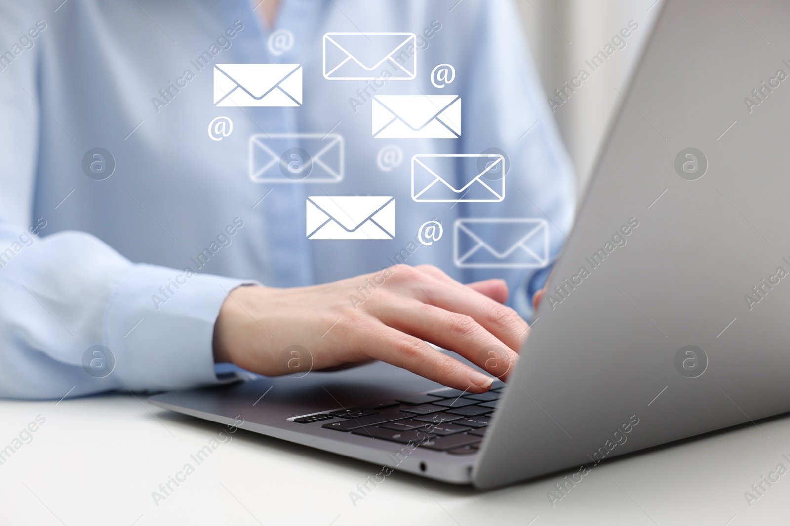 Image of Woman using laptop at table, closeup. E-mail address signs and envelopes over computer