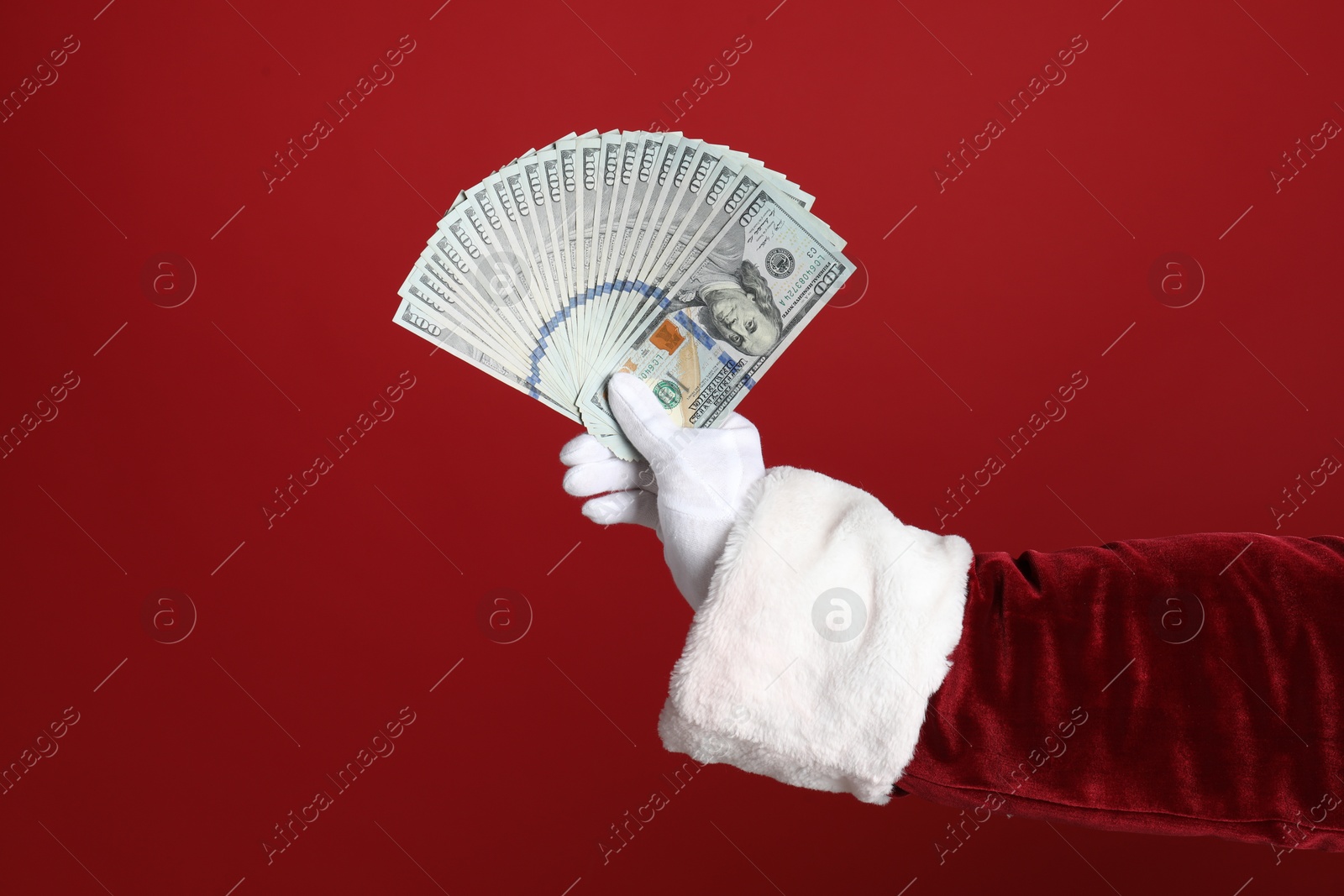 Photo of Santa holding dollar bills on red background, closeup