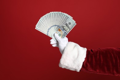 Santa holding dollar bills on red background, closeup