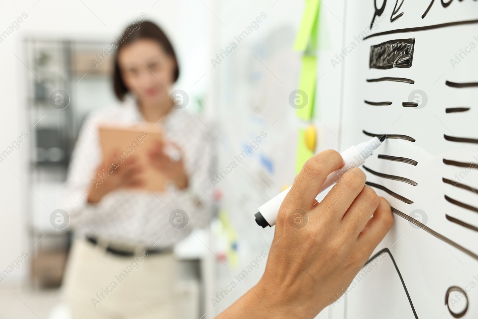 Photo of Developing UI design. Man and woman drawing website wireframe on whiteboard indoors, selective focus