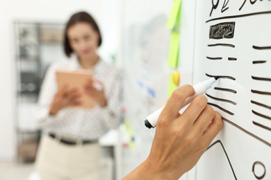 Developing UI design. Man and woman drawing website wireframe on whiteboard indoors, selective focus