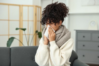 Photo of Cold symptom. Young woman with tissue at home