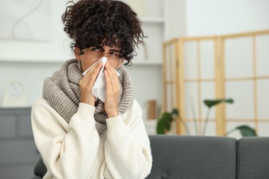 Photo of Cold symptom. Young woman with tissue at home, space for text