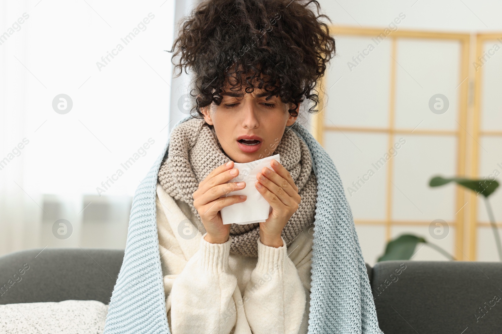 Photo of Cold symptom. Young woman with tissue at home