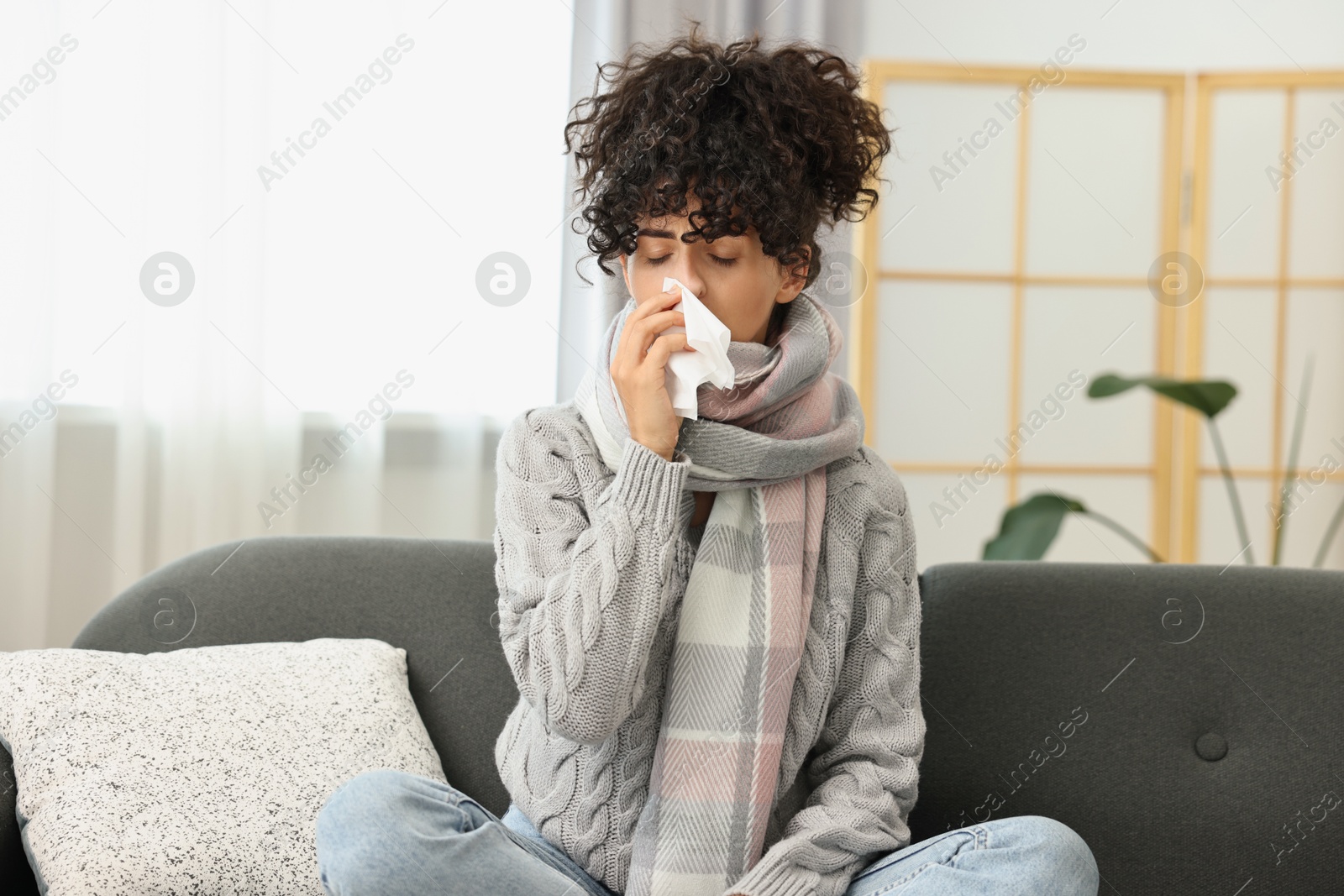 Photo of Cold symptom. Young woman with tissue at home